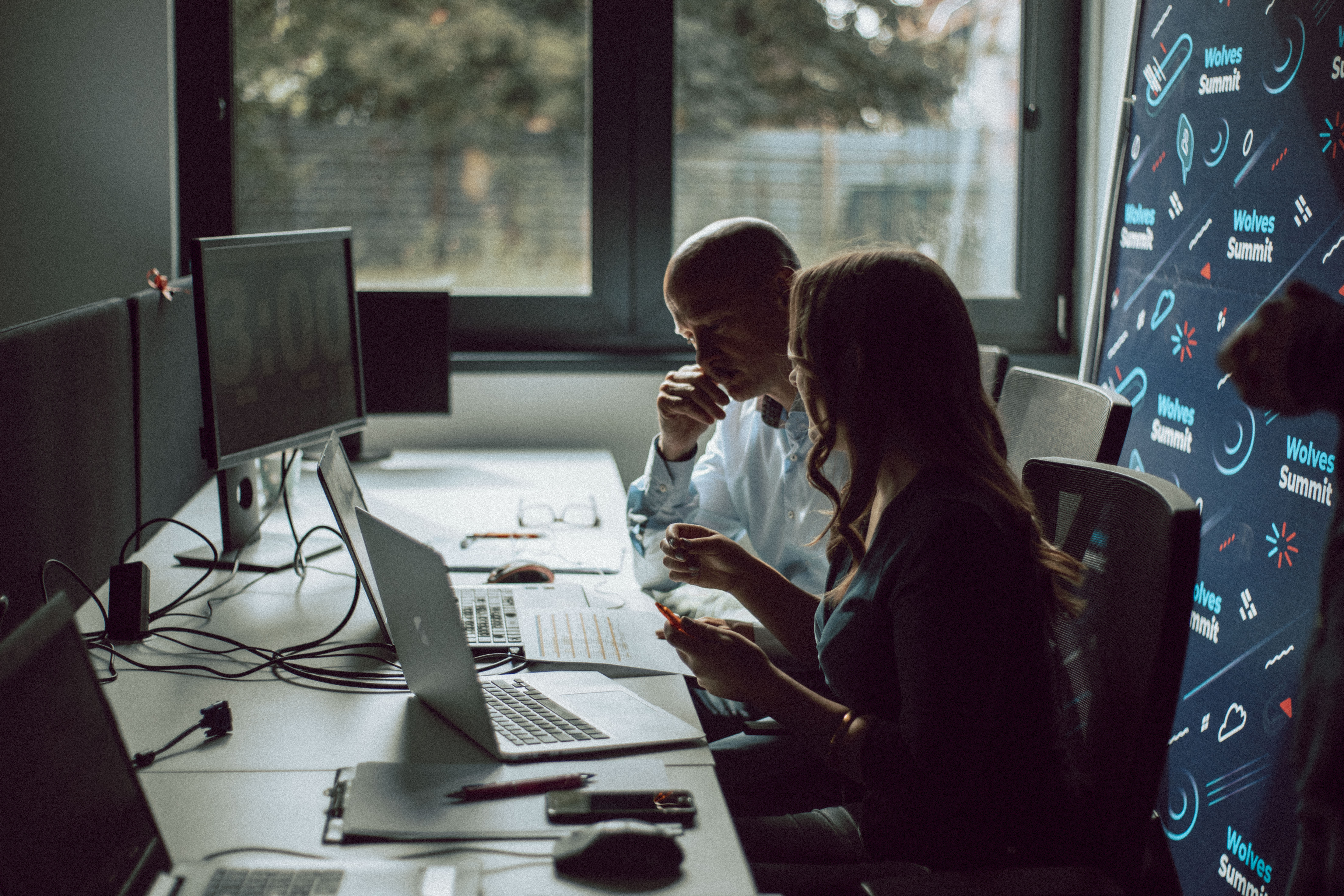 A man and a women working in front of the computer. 